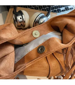 Close-up of the double magnetic clasp design on a brown suede fringe hobo bag