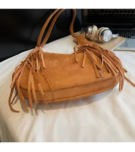 Detail of a brown suede hobo bag with long bohemian tassels and smooth shoulder strap