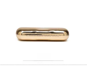 Detail view of the metal box bag's bottom featuring a gold hinge and linear texture