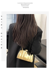 Detailed view of a gold pleated metal clutch bag with a delicate chain strap on a model