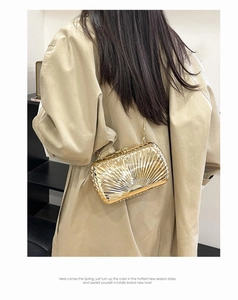 Macro detail of golden shell texture on metallic clutch bag with elegant chain strap