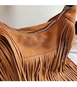 Detail of soft brown faux suede texture and long fringe tassels on the shoulder bag