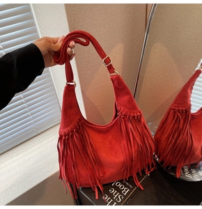 Detail of red suede hobo bag featuring bohemian fringe tassels and gold metal hardware