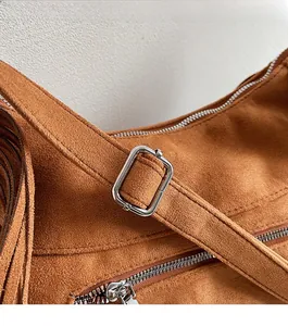 Detailed close-up of the silver polished buckle and zipper on a brown suede shoulder bag