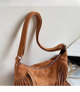 Detail of adjustable strap and silver zipper on brown tassel suede shoulder bag