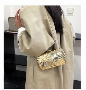Detail of gold metal shell clutch bag with radial pleats and shiny metallic finish