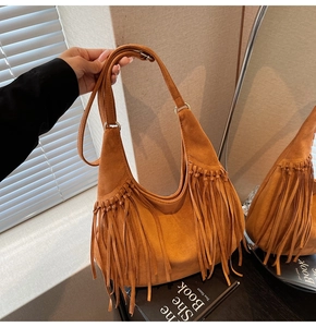 Detail of caramel suede hobo bag featuring long tassels and retro metal ring hardware