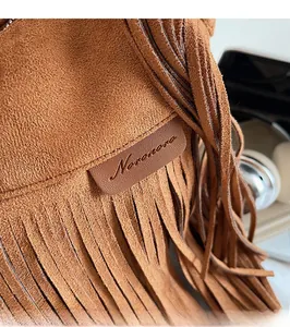 Close-up of brown suede hobo bag detailing fringe design and textured leather label