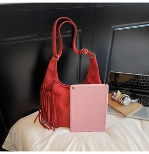 Close-up of red suede hobo bag featuring dense fringe tassels and adjustable strap