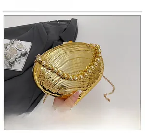 Detail of golden shell-shaped evening clutch with textured finish and beaded handle
