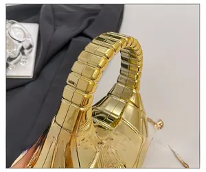 Detail showing high-gloss gold hardshell bag with textured grid pattern and thick handle