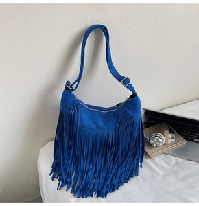 Macro view of blue suede shoulder bag with long fringes and silver metal zipper details