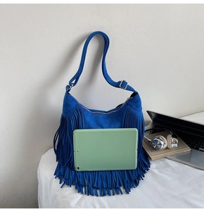Blue suede hobo bag with fringe details showing capacity to hold a tablet device