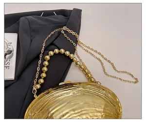 Detail of shell evening bag showing golden beaded handle and elegant chain strap