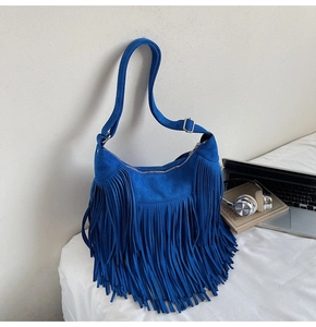 Detail of royal blue suede hobo bag featuring dense fringe tassels and silver zipper