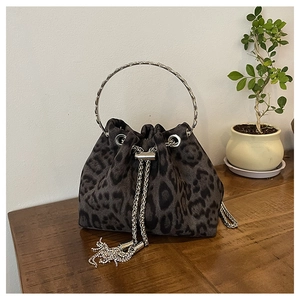 Detail of leopard print bucket bag with metal ring handle and rhinestone tassels