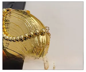 Detailed close-up of golden shell evening bag with beaded handle and chain strap