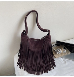 Detailed close-up of dark brown suede fringe bag with bohemian style tassels and silver zipper