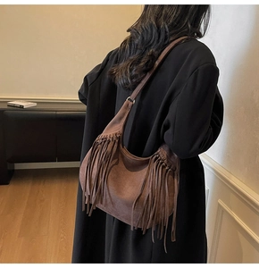 Detail of brown suede hobo bag with long tassels and adjustable shoulder strap