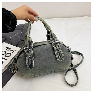 Macro view of washed denim crossbody bag featuring silver buckles and strap details