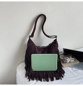 Close-up of chocolate brown suede shoulder bag with long fringes and adjustable strap