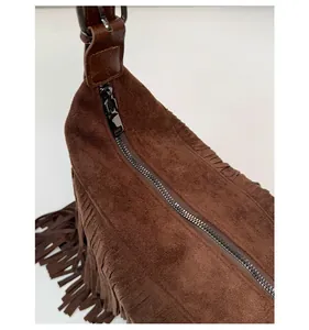 Detailed macro of a dark brown suede tassel bag with custom metal zipper pull and smooth closure