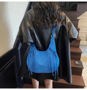 Detail of bright blue suede fringe shoulder bag with bohemian tassels and metal buckle