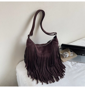 Close-up of vintage dark brown fringe shoulder bag with matte texture and wide strap