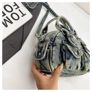 Detail of washed denim crossbody bag featuring utility multi-pockets and silver hardware
