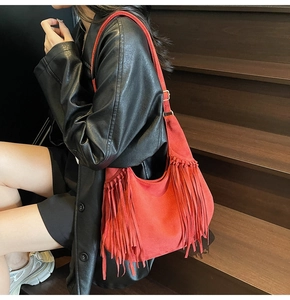 Macro shot of red frosted suede shoulder bag with dense fringe details and gold buckles
