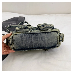 Detailed bottom view of a vintage washed denim crossbody bag with cargo pockets