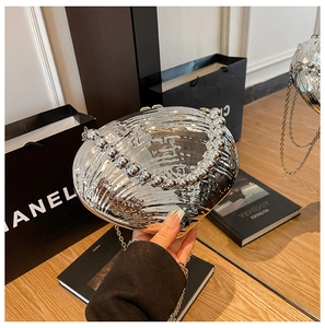 Détail du sac de soirée coquillage argenté avec poignée en perles et texture miroir