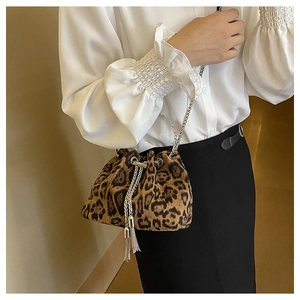 Detail of leopard print bucket bag with silver drawstring chain strap on white outfit