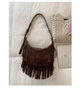 Detail of dark brown suede crossbody bag featuring long bohemian tassels and adjustable strap