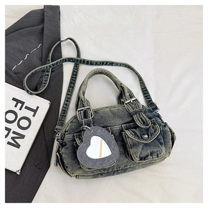 Close-up of vintage denim handbag with heart mirror charm and washed texture detail