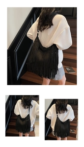 Detail of black suede-style hobo bag featuring long flowing fringes and wide shoulder strap