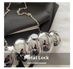 Detail of silver spherical acrylic bag featuring a shiny mirror finish and hardware clasp
