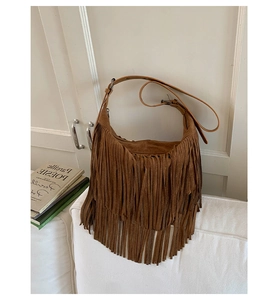 Detail of bohemian brown tassel shoulder bag with soft suede texture and metal strap rings