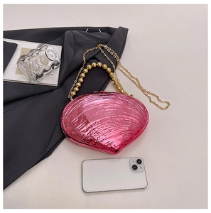 Vue détaillée du sac pochette coquillage rose en acrylique avec chaîne dorée et smartphone
