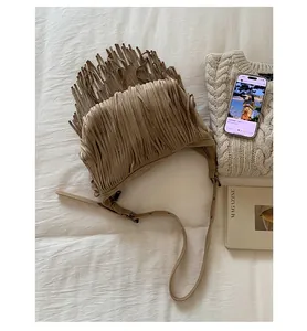 Detail of brown suede crossbody bag with long fringes and metal adjustment buckle