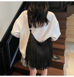 Detail of black fringe shoulder bag with long swaying tassels and soft matte suede texture