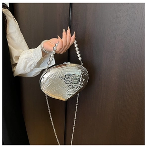 Détail du sac de soirée coquillage argenté avec poignée en perles et texture plissée