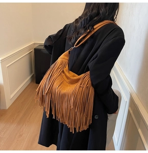 Detail of vintage brown tassel shoulder bag with soft suede texture and bohemian fringe