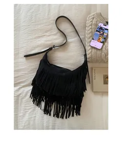 Detail of bohemian black fringe crossbody bag with suede texture and adjustable strap