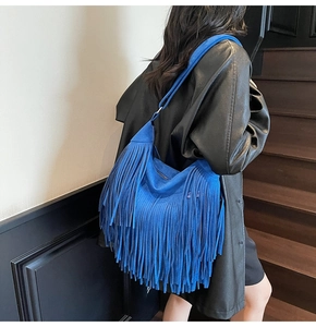 Detail of Klein blue suede shoulder bag with dense fringe accents on model