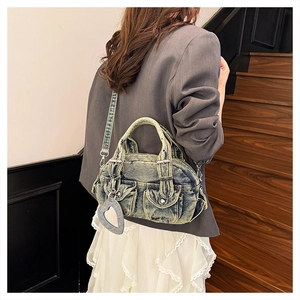 Close-up of washed denim handbag with cargo pockets and heart pendant detail