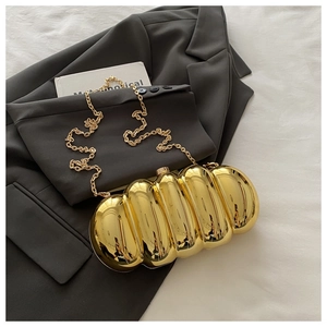 Macro shot of wavy gold metallic clutch with mirror finish and fine chain strap