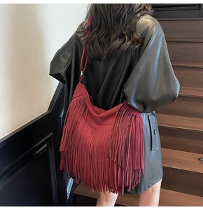Close-up of bohemian burgundy fringe shoulder bag in faux suede on a model