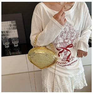 Détail du sac de soirée doré en forme de coquillage avec poignée perle et chaîne
