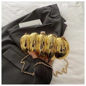 Detailed close-up of the gold metallic clutch with segmented design and chain strap